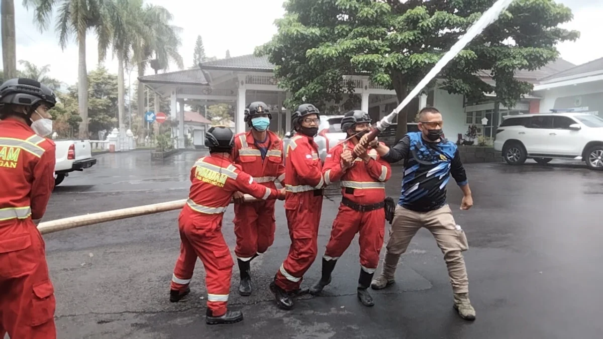 CAIRAN DISINFEKTAN. Petugas Damkar melakukan penyemprotan cairan disinfektan di kompleks perkantoran Setda Kuningan, akhir pecan kemarin