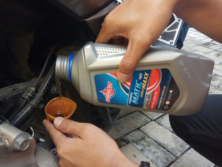 Foto Orang Memasukkan Oli ke Corong dengan Merek Federal Matic Ecomaxxx.. Cara Ganti Oli Honda BeAT di Rumah, Mudah Banget!. Foto: Federaloil.co.id